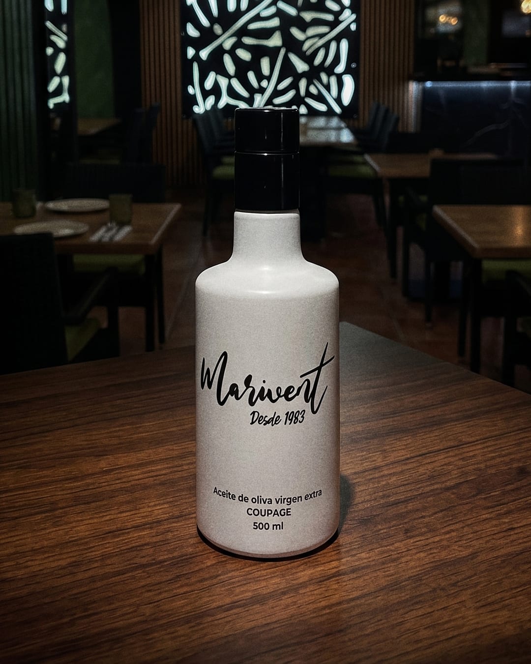 Botella de aceite de oliva virgen extra de marca propia Marivent, desde 1983, sobre una mesa del restaurante